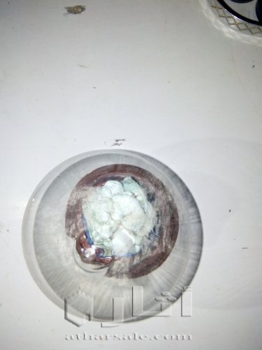 حجر فيروز موضوع داخل حافظه زجاجية بقاعدة خشب